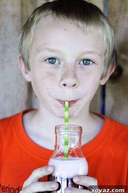 Calorie-Free Hibiscus Lime Soda | A child happily drinking homemade hibiscus lime soda from a straw