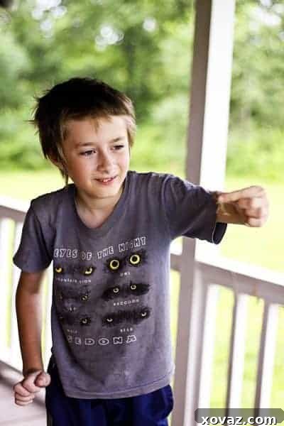 Leif, a young boy, intently observes a crawfish held carefully in his hands, showcasing a moment of calm focus and respectful engagement with nature amidst the excitement of the family's creek adventure.