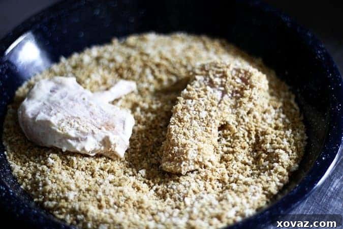 Dredging chicken in seasoned panko crumbs