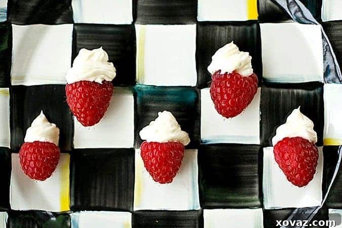 Close-up of One Bite Cheesecake Stuffed Raspberries with Chambord. Creamy cheesecake filling artfully piped into fresh raspberries, garnished with a small cap of filling.