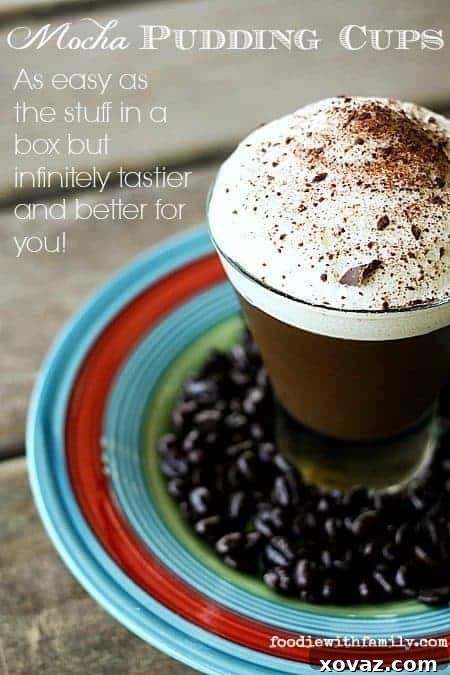 Hand holding a glass jar filled with Rich Mocha Pudding Cups, topped with whipped cream and chocolate shavings.