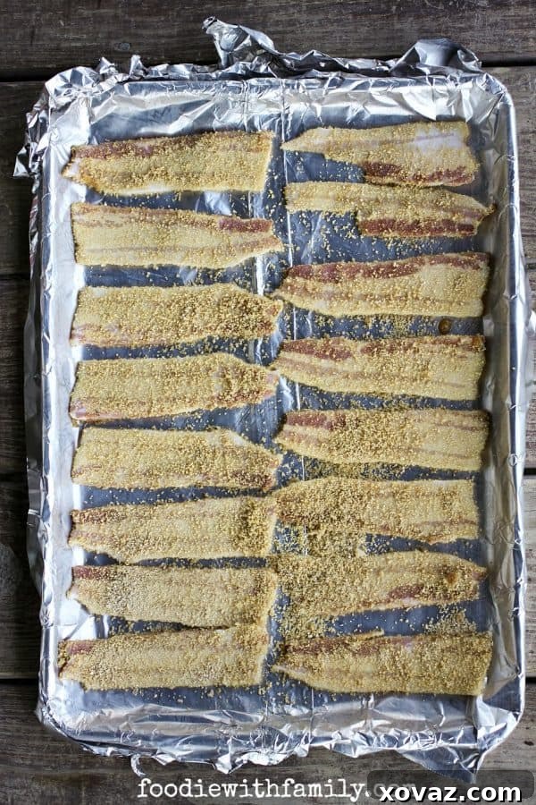 Sticky Sweet Maple Bacon 3 Homemade Maple Candied Bacon slices being arranged on a baking sheet, coated generously with maple sugar, ready for the oven.