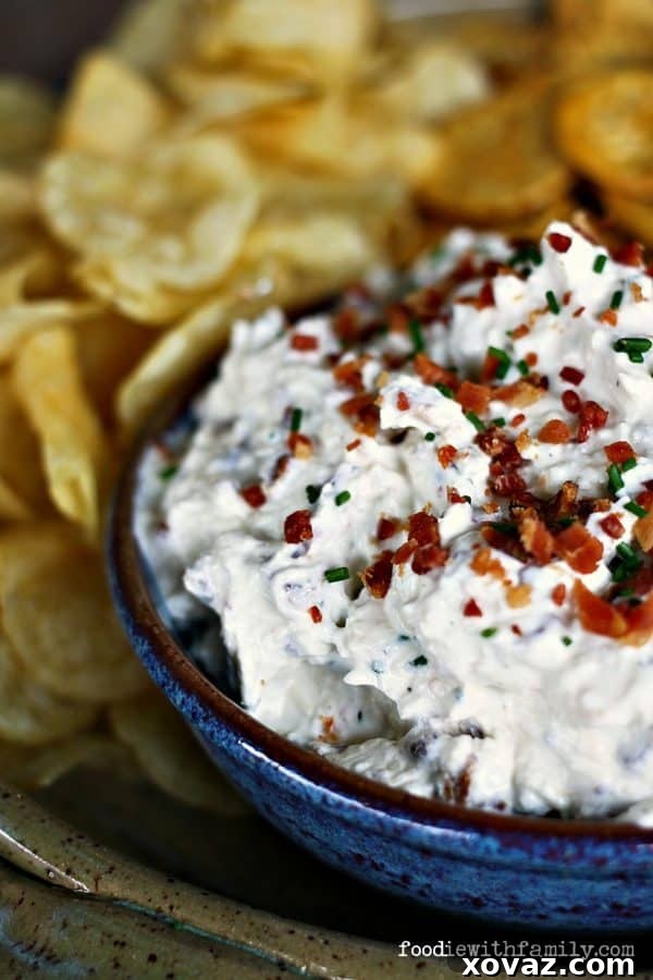 Rich and creamy Bacon Cheddar Chive Dip, garnished with extra bacon and chives, ready to be served with chips.