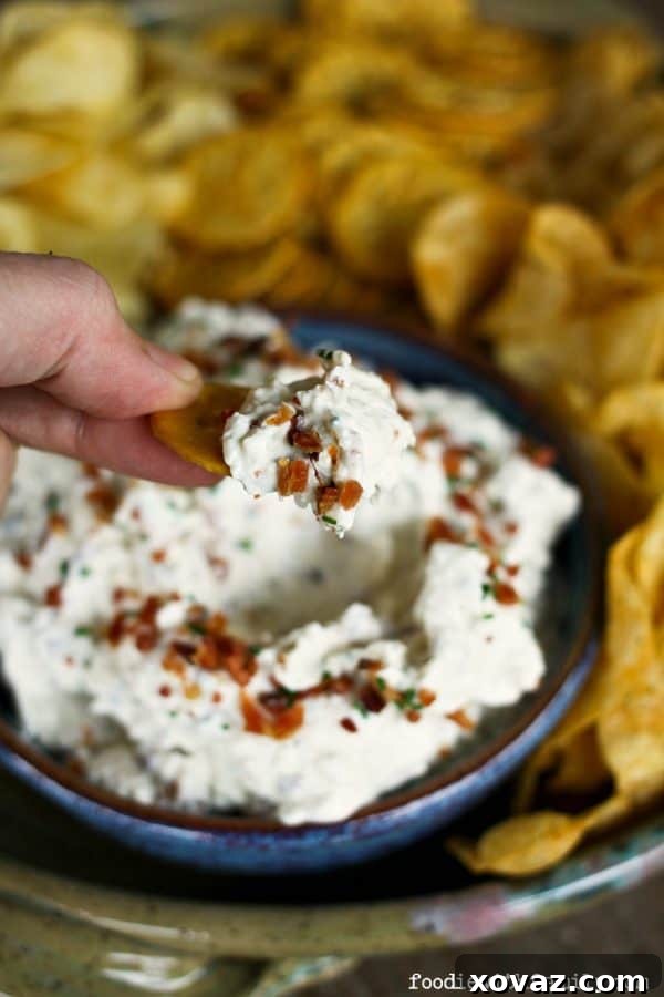 A freshly made batch of homemade sour cream, bacon, cheddar, and chive dip, showcasing its creamy texture and rich ingredients.