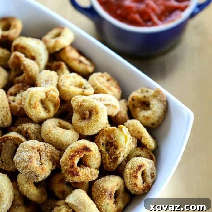 An overhead shot of Toasted Tortellini Bites on a rustic wooden board, accompanied by a bowl of marinara sauce.
