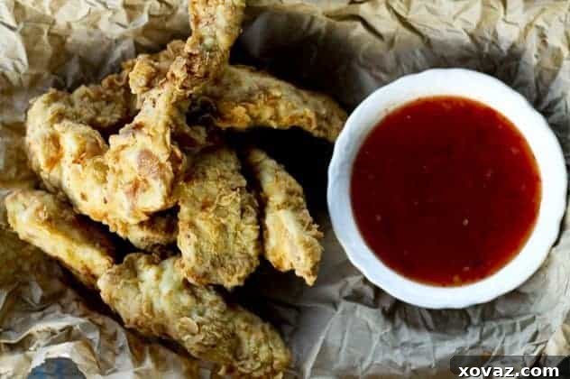 extra-crispy-fried-chicken-strips Golden brown, perfectly crispy fried chicken tenders resting on a cooling rack, ready to be served.