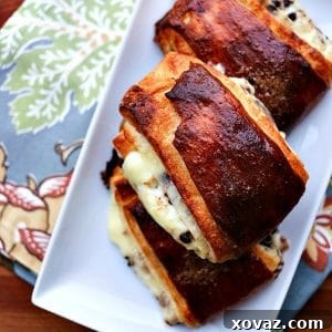 plie au chocolat, dark brown laminated pastry with pastry cream and mini chocolate chips on white plate, light blue towel with multi colour floral pattern, mahogany wood cutting board