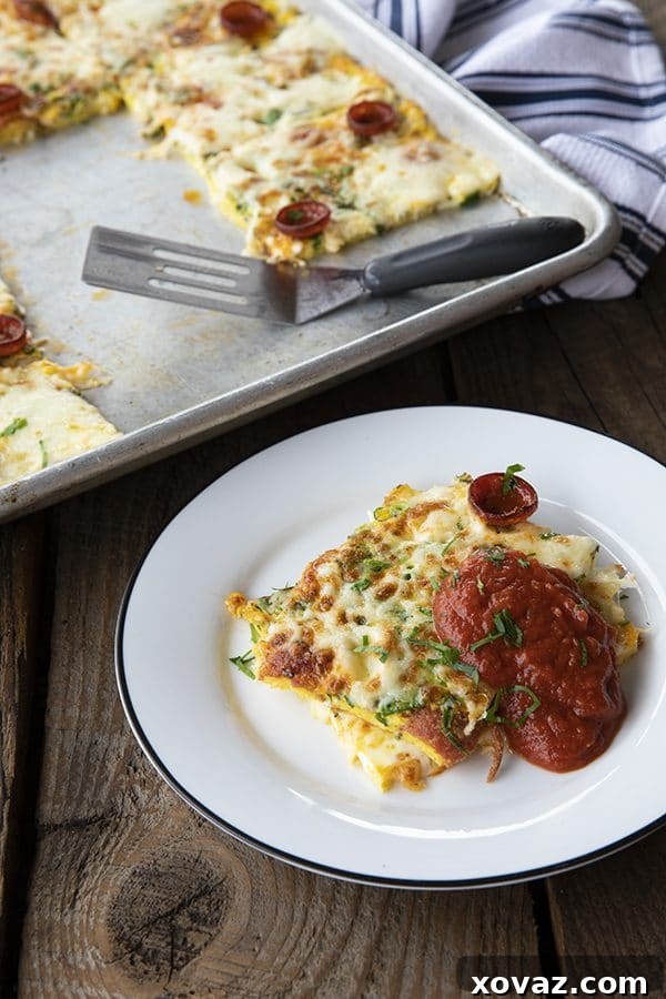 A top-down shot of a beautifully cooked Baked Pizza Frittata, cut into perfect squares on a half sheet pan. The surface is golden with melted, slightly browned mozzarella and crispy pepperoni, ready to be served. A small bowl of marinara sauce is visible in the corner.