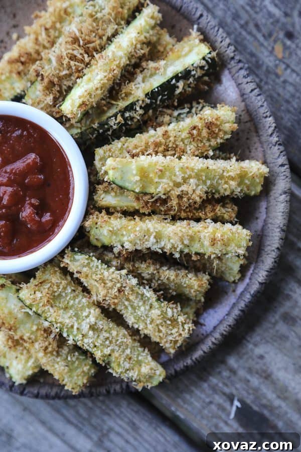 Irresistibly crispy, crunchy, and absolutely habit-forming; a close-up of golden brown Crispy Baked Parmesan Zucchini Fries on a baking sheet, ready to be devoured.