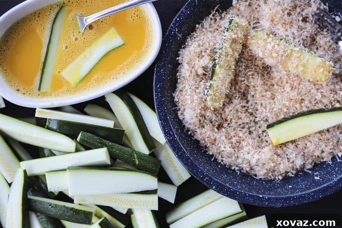 A serving of golden brown Crispy Baked Parmesan Zucchini Fries in a white bowl, showcasing their irresistible texture and perfect for dipping.