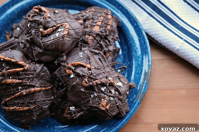 Assortment of Caramel Stuffed Dark Chocolate Covered Pretzels on parchment paper with a dusting of sea salt