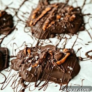 Caramel Stuffed Chocolate Covered Pretzels drizzled with caramel candy, chocolate, maldon sea salt flakes on parchment paper