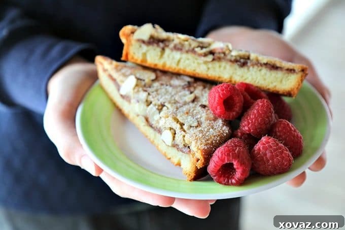 Nutella Raspberry Bostock on an antique white dessert plate with bright green rim, almond crusted, dusted with powdered sugar, raspberries on plate.
