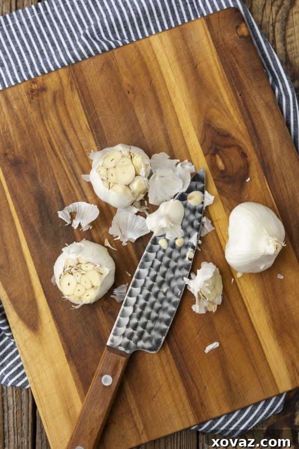 The process of preparing garlic for roasting, showing the top of the bulb sliced off to expose the cloves.