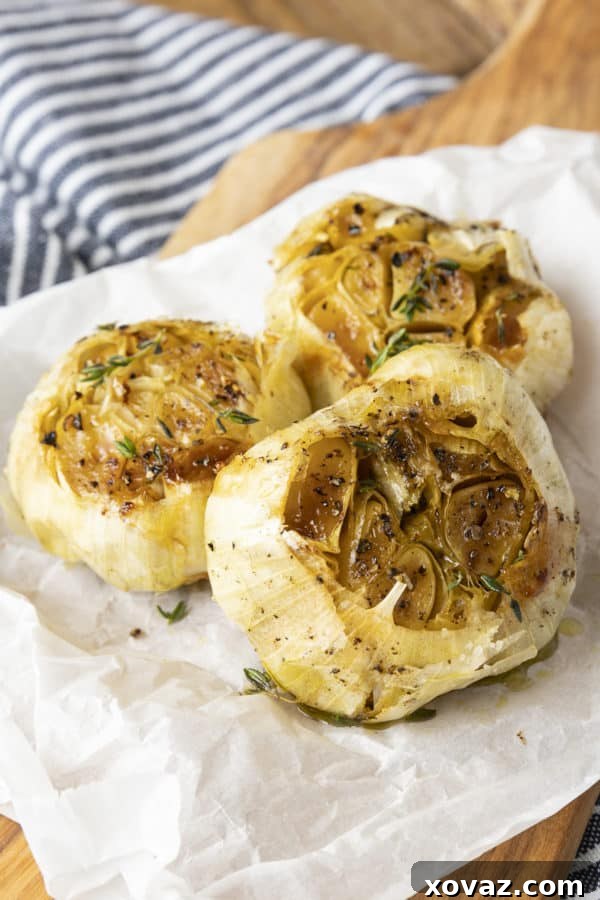 Squeezing soft, golden roasted garlic cloves from their papery skin, demonstrating how easily they are extracted.