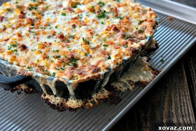A golden, bubbling hot corn dip in a cast iron skillet, filled with sweet corn, tender chicken, crispy bacon, mild Hatch chiles, and fresh green onions, all enrobed in a creamy, cheesy ranch sauce, ready to be served at a party.
