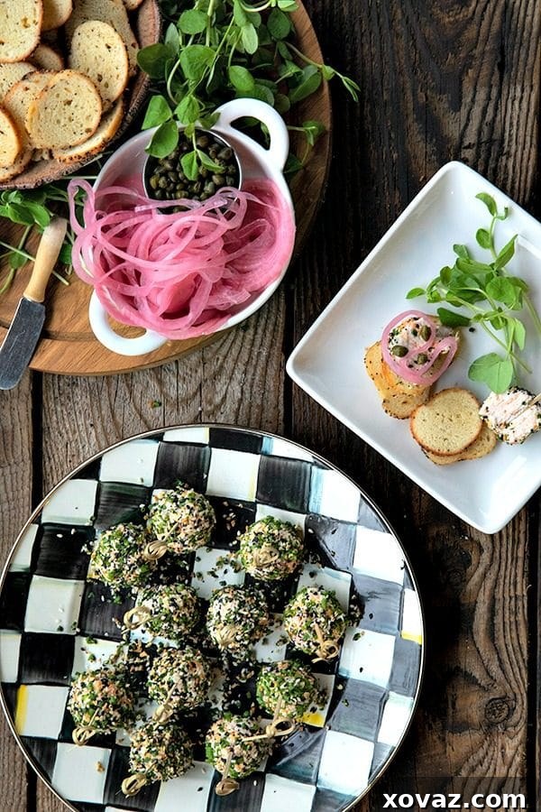 Everything Bagel Mini Cheese Bites 3 A close-up view of a hand holding a mini cheese ball on a toothpick, showcasing the exterior coated in chives and everything bagel seasoning, ready for serving.