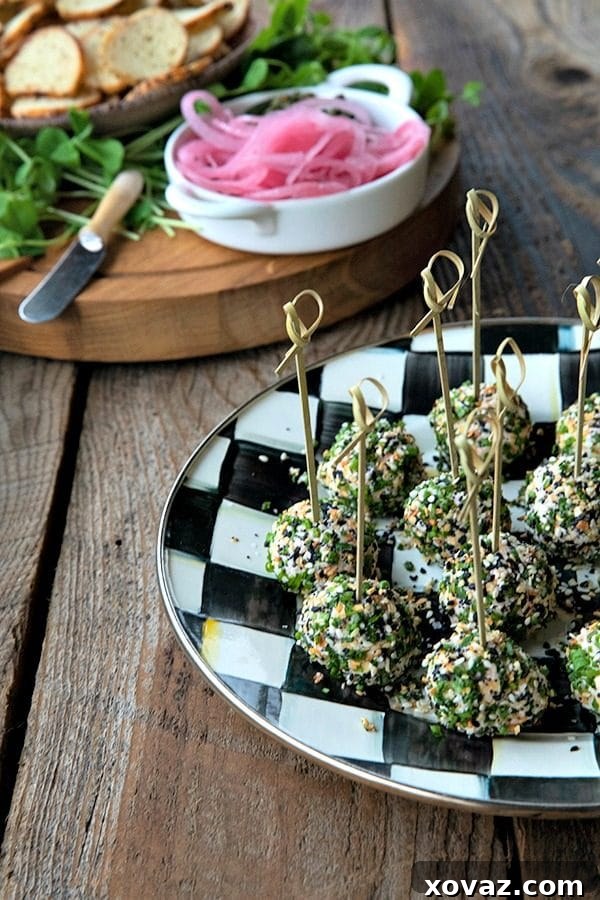 Everything Bagel Mini Cheese Bites 4 A festive platter of mini cheese balls with smoked salmon and everything bagel seasoning, surrounded by fresh herbs and crackers, ideal for holiday entertaining.