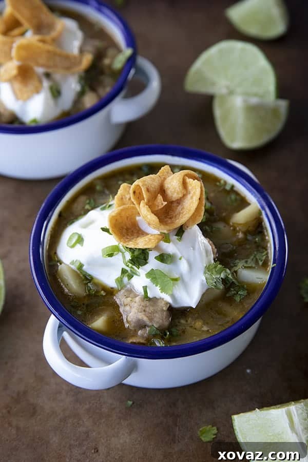 Hearty Pork Green Chili 3 Close-up of Pork Green Chili in a white bowl, showcasing tender pork, beans, and chiles, ready to be enjoyed.
