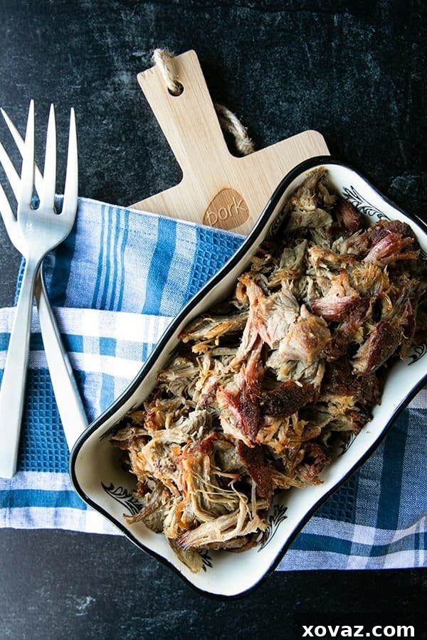 Cooked pork shoulder with steam rising, indicating tenderness and readiness for shredding.