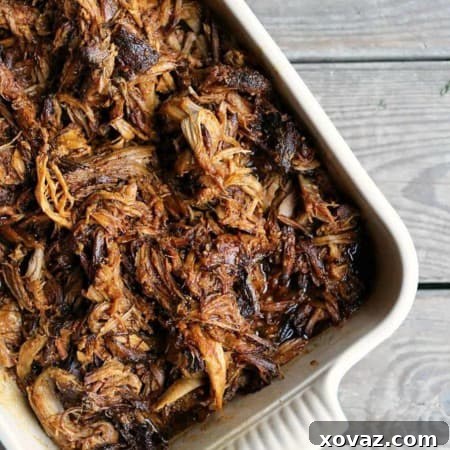 Cooked pork shoulder in a slow cooker, ready for shredding to make pulled pork.