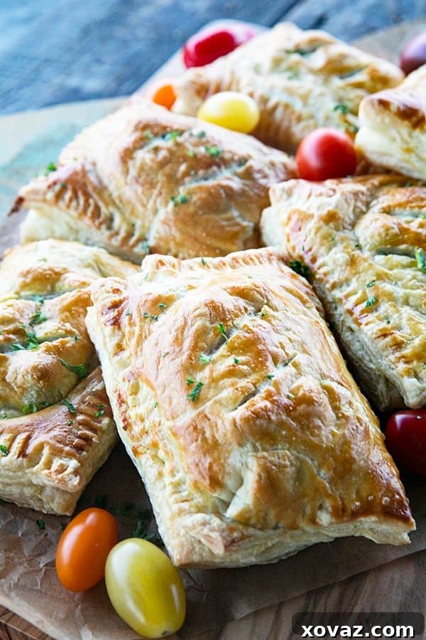 Golden Cheesy Egg and Sausage Breakfast Pockets 2 Flaky Breakfast Hot Pockets filled with cheesy scrambled eggs and sausage links, served on a cutting board with fresh cherry tomatoes.