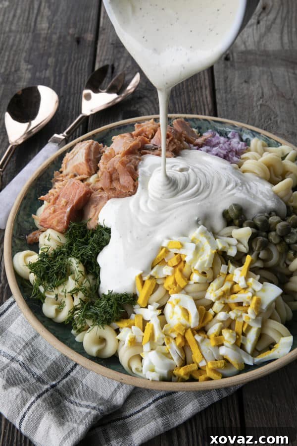 Zesty Salmon Pasta Salad 9 Cooked pasta, smoked salmon, and other ingredients being combined in a large mixing bowl.