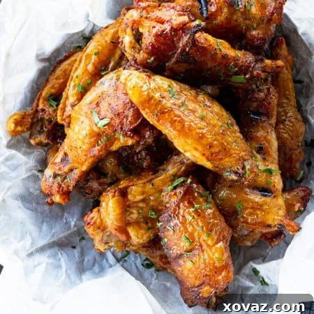 Smoky Crispy Chicken Wings 7 A close-up of a stack of perfectly smoked chicken wings on a wooden board.
