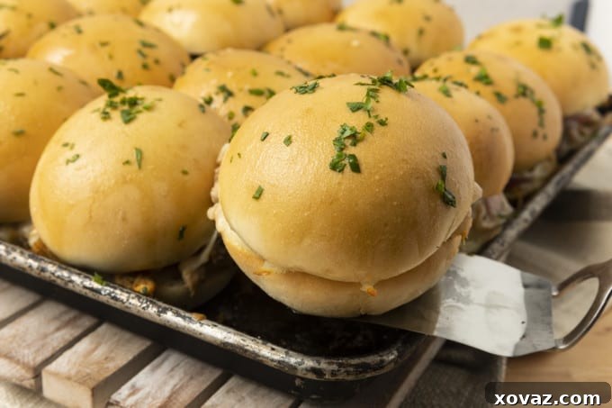 A vibrant serving platter piled high with freshly baked BBQ Chicken Sliders, garnished with fresh parsley, ready to be enjoyed as an appetizer or meal.