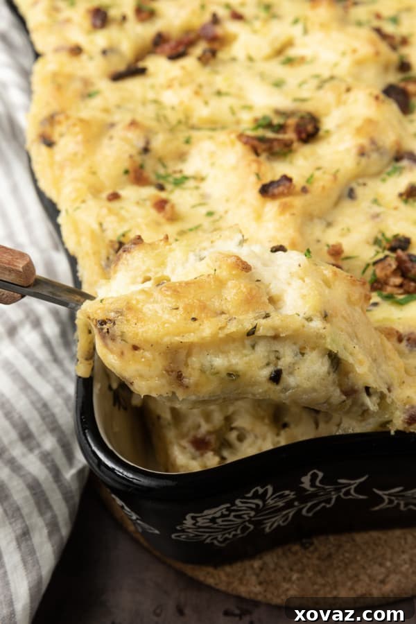 A large baking dish filled with golden-crusted, creamy Twice Baked Mashed Potatoes, garnished with fresh herbs and bacon.