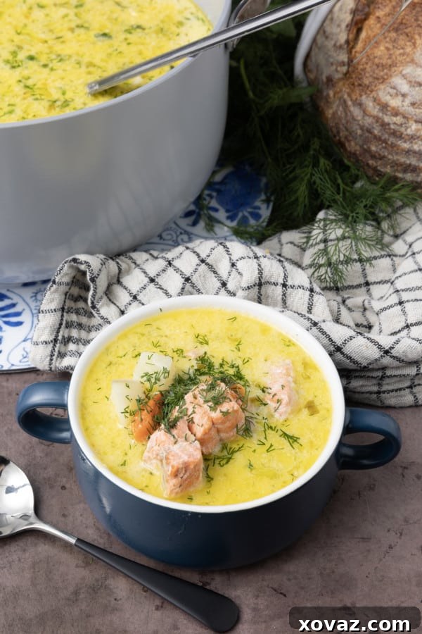 A bowl of hot Finnish Salmon Soup with a spoon, showing the creamy texture and chunks of ingredients.