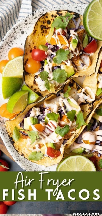 A plate of two Air Fryer Fish Tacos garnished with fresh lime and various toppings