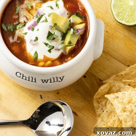 A vibrant bowl of 5-Ingredient Taco Soup garnished with fresh cilantro, a dollop of sour cream, and crispy tortilla chips, photographed from above.