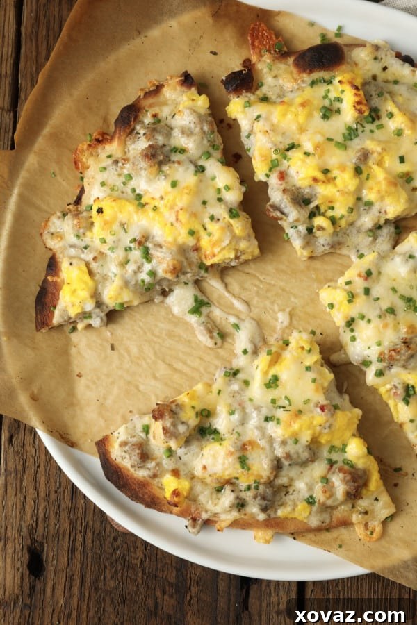 Sausage Gravy Breakfast Pizza on a serving board, garnished with fresh chives, showcasing cheesy scrambled eggs and creamy gravy on a golden, chewy crust.