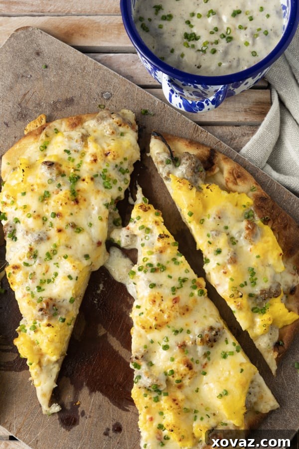 Key ingredients for Sausage Gravy Breakfast Pizza displayed on a wooden surface: eggs, butter, cheese, milk, salt, pepper, chives, naan bread, and a bowl of sausage gravy.