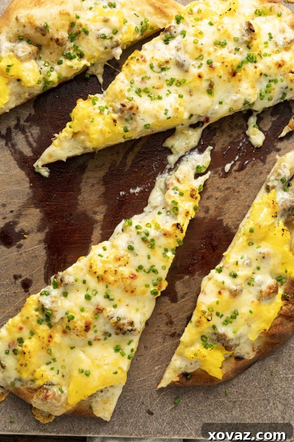 A freshly baked Sausage Gravy Breakfast Pizza, golden and bubbling, garnished generously with vibrant green chives, ready to be sliced.