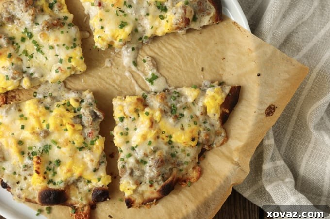 A sliced Sausage Gravy Breakfast Pizza on a baking sheet, showcasing the crispy edges of the crust and the appealing layers of toppings.