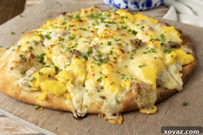 A perfectly cooked slice of Sausage Gravy Breakfast Pizza, showcasing the bubbly gravy, melted cheese, and fluffy eggs on a golden crust.