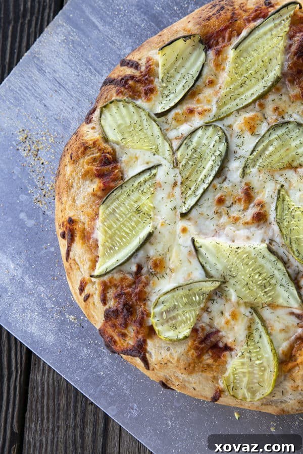 A delightful Pickle Pizza with creamy garlic dill sauce, molten cheese, and sliced dill pickles.