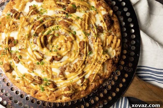 A vibrant, freshly baked Chick-fil-A Pizza, generously topped with chicken, waffle fries, and cheese.