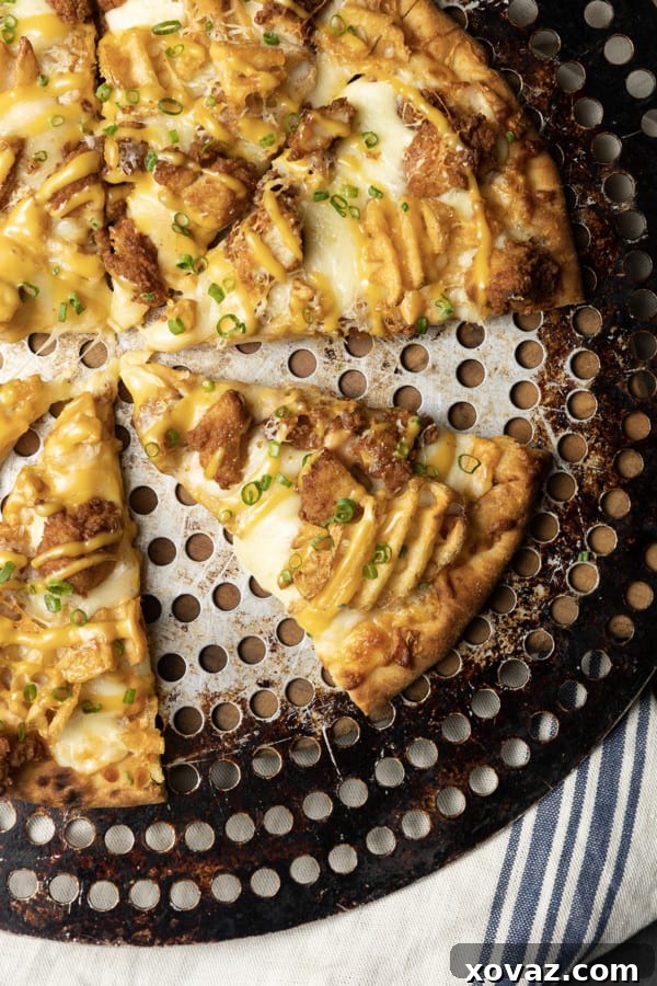A hand drizzling Chick-fil-A sauce over a freshly baked pizza, topped with chicken nuggets and waffle fries.