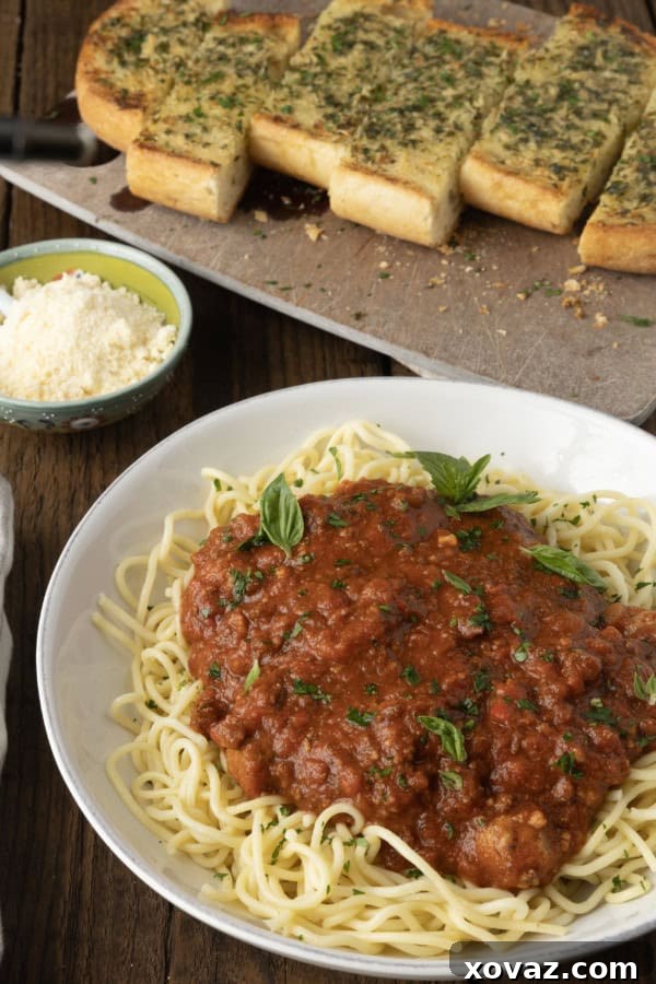 A bowl of homemade crockpot spaghetti sauce ready to be served, garnished with fresh basil leaves.