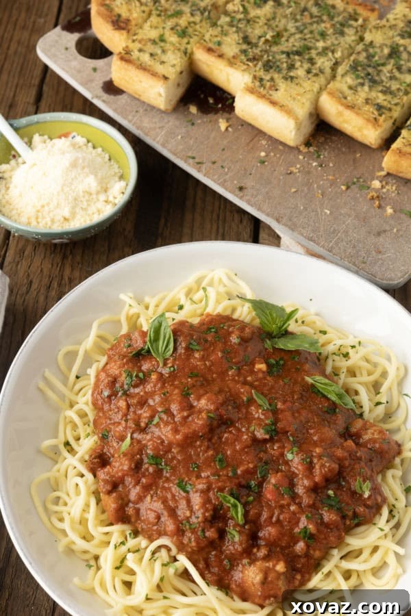 A beautifully plated dish of spaghetti with homemade crockpot sauce, fresh herbs, and a side of garlic bread, ready for a family meal.