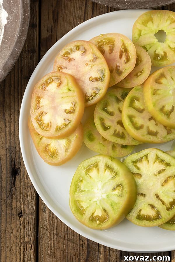 Crispy Air Fryer Fried Green Tomatoes 5 Sliced green tomatoes on a white plate on a rustic wooden table