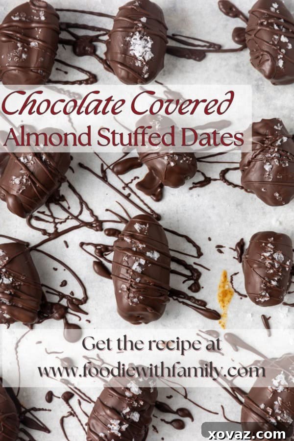 A beautifully presented chocolate covered almond butter stuffed date, garnished with sea salt, on a parchment-lined sheet pan. The image has a text overlay with the title: 'Creamy Almond Butter Filled Chocolate Covered Dates'.