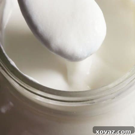 A close-up view of homemade cultured buttermilk in a glass jar, demonstrating its rich, thick texture.