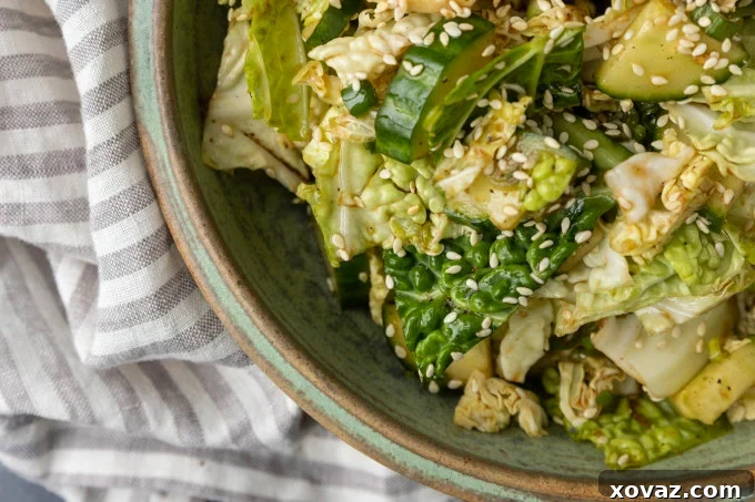 japanese cabbage and cucumber salad in a bowl, garnished with sesame seeds and green onions