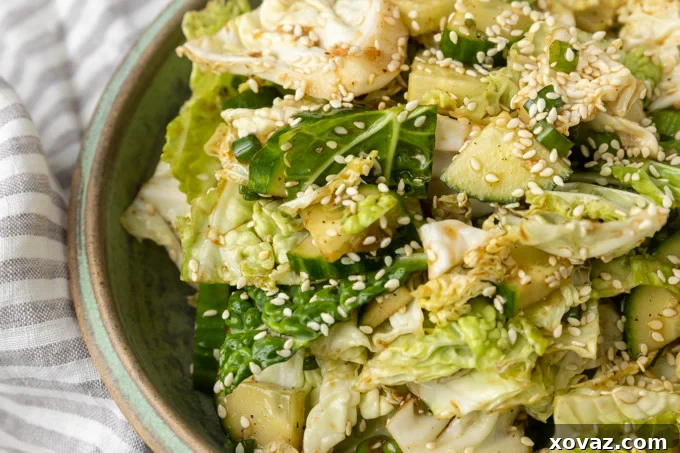 Japanese cabbage and cucumber salad with the dressing being tossed in a mixing bowl