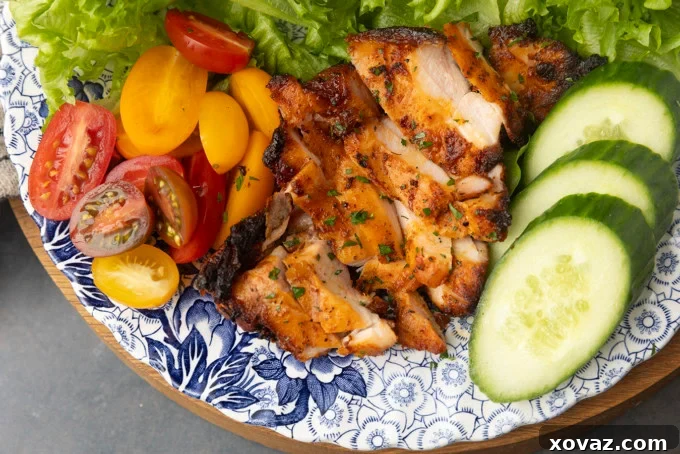 Perfect Pellet Grilled Chicken Thighs 2 Crispy, juicy pellet grill chicken thighs served on a plate with fresh lettuce, tomatoes, and cucumbers.