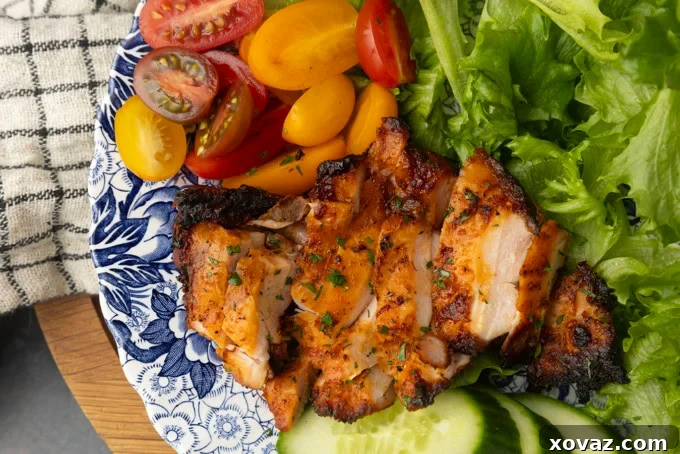 Perfect Pellet Grilled Chicken Thighs 4 Plated pellet grill chicken thighs, garnished with fresh salad components like lettuce, tomatoes, and cucumbers, ready for serving.